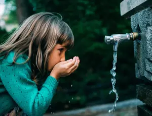 Fillette buveant de l'eau à une fontaine
