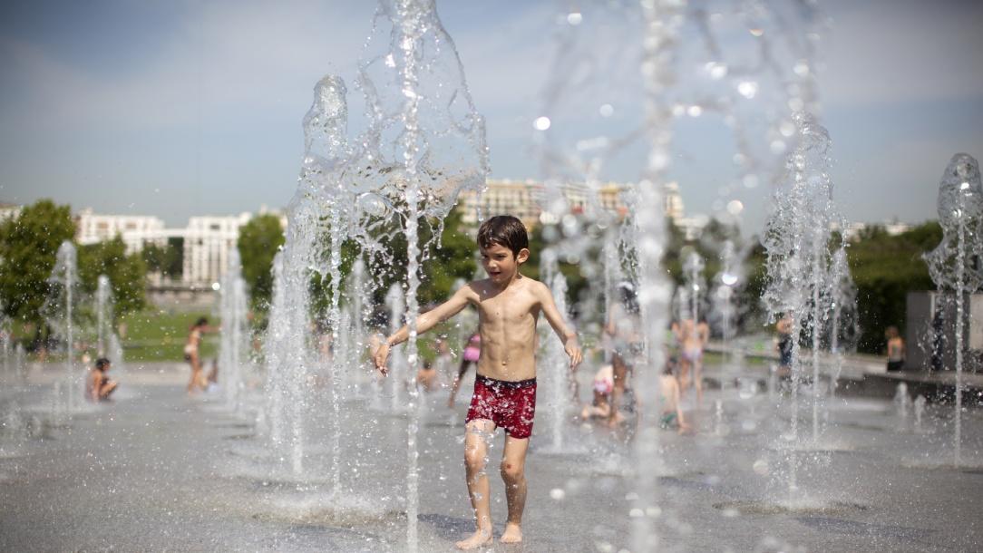 Jeune garçon jouant dans une fontaine à eau en ville