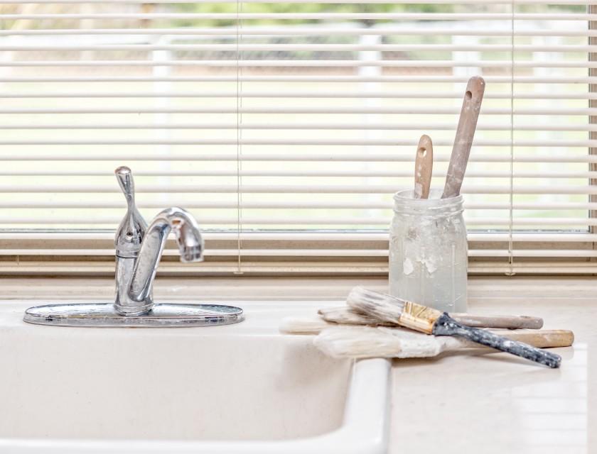 Pinceaux et peinture près d'un robinet d'eau
