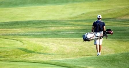 Golfeur de dos marchant sur le green