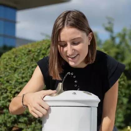 jeune femme buvant de l'eau à une fontaine