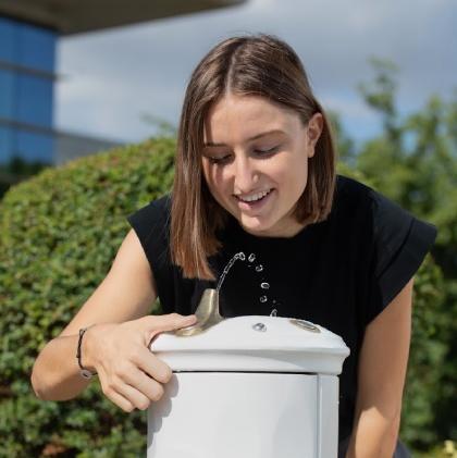 jeune femme buvant de l'eau à une fontaine