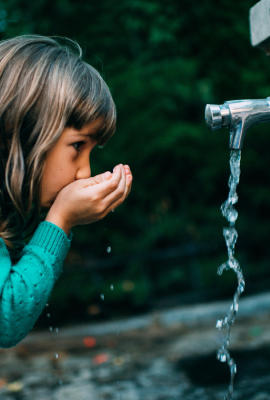 Petite fille buvant de l'eau à une fontaine