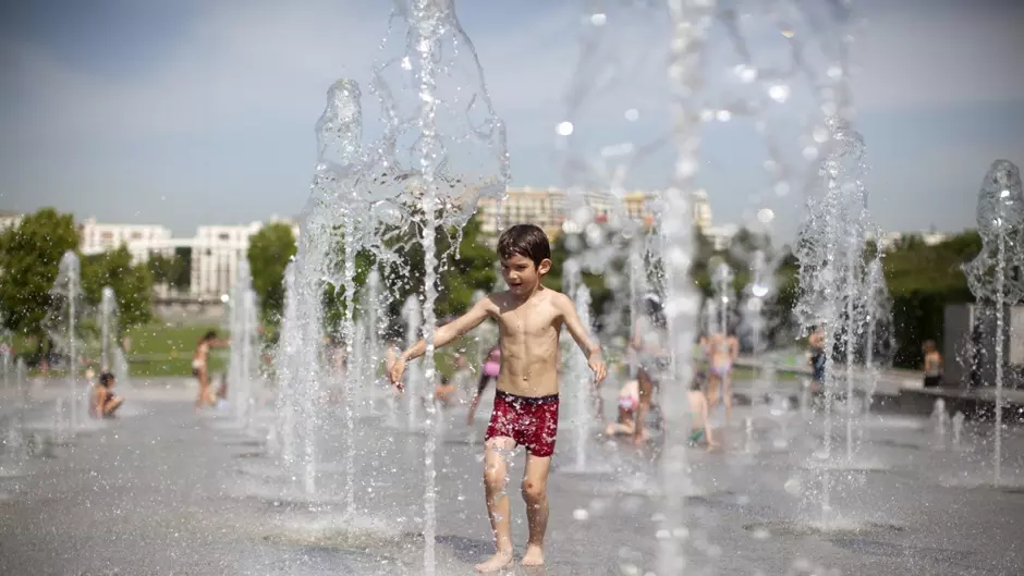 Jeune garçon jouant dans une fontaine à eau en ville