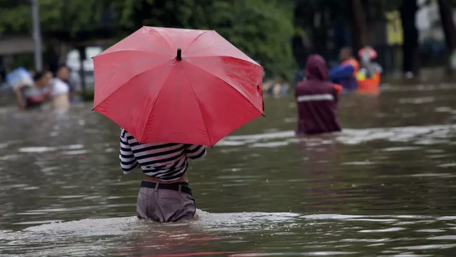 Personne de dos avec un parapluie se déplaçant dans l'eau après une inondation