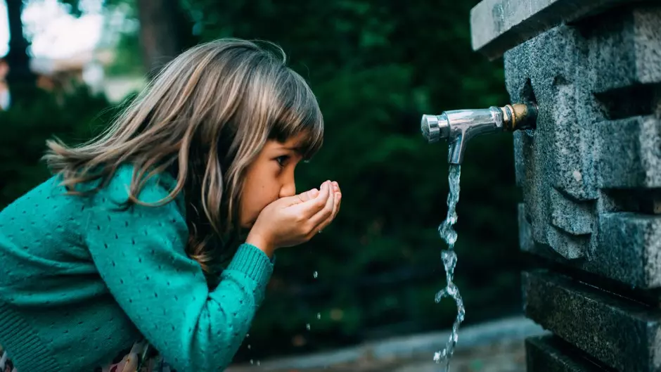 Fillette buveant de l'eau à une fontaine