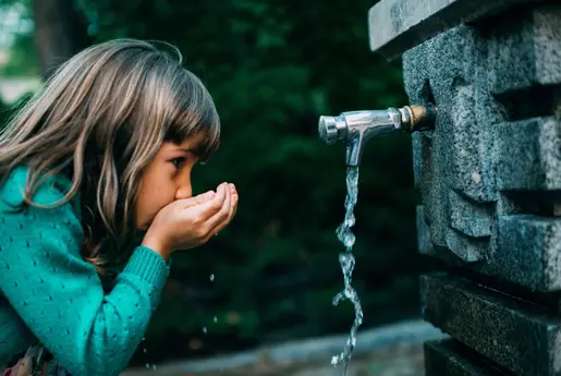Enfant buvant l'eau d'une fontaine
